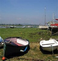 Boats moored on dry land at low tide in Chichester Harbour, West Sussex.